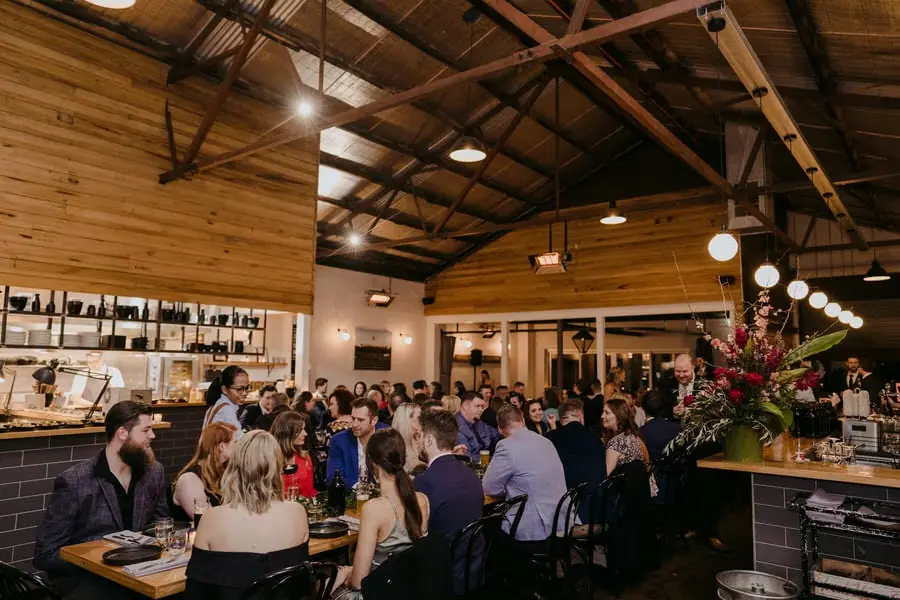 Guests seated at long reception tables beneath exposed timber beams