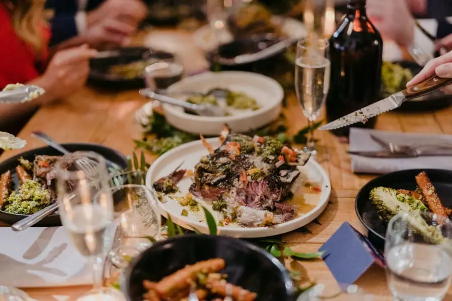 Shared dishes being served among plates and glasses on a reception table