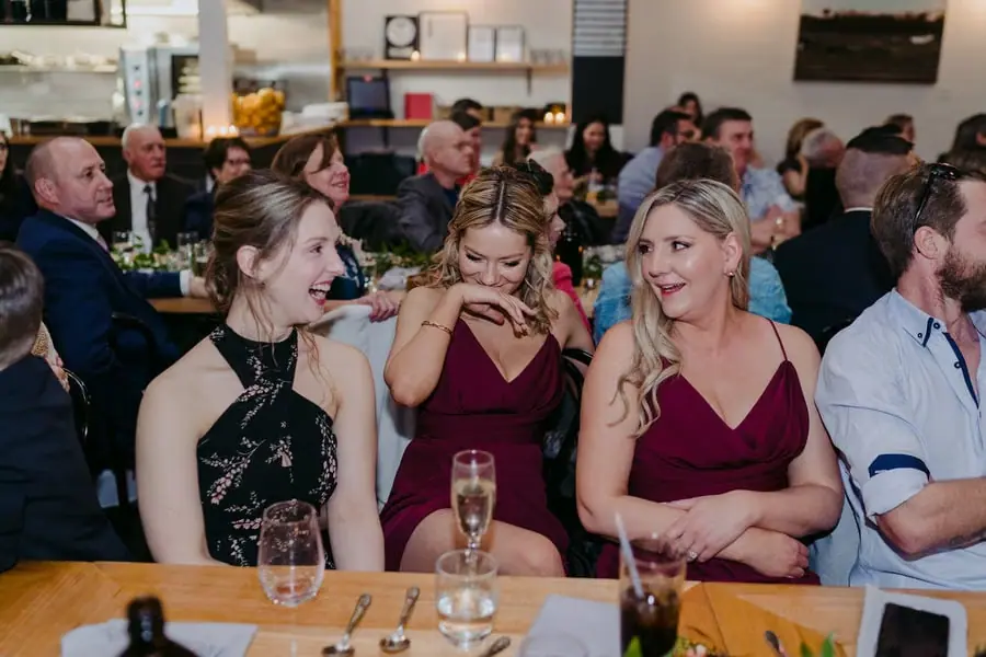 Bridesmaids chatting at a reception table with a young girl between them