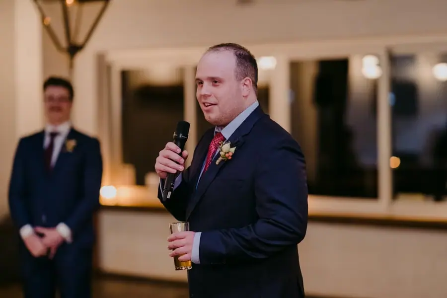 Guest speaking into a microphone with a drink in his other hand