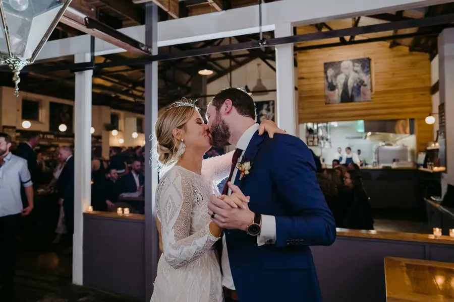Bride and groom kissing while dancing together at the reception