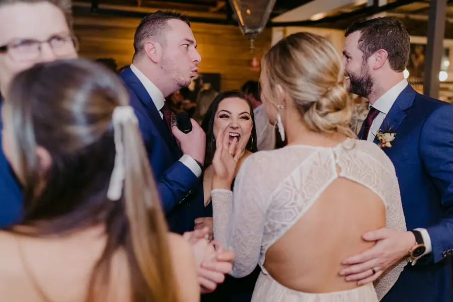 Bride and groom laughing with guests gathered closely around them