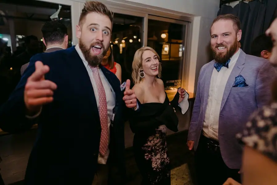 Guests laughing and gesturing toward the camera on the dance floor
