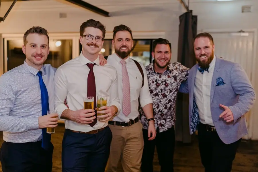 Five men posing together with drinks inside the reception