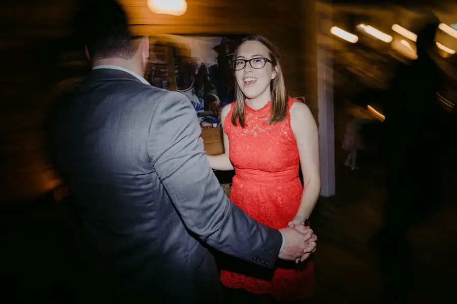 Woman in a red dress and glasses dancing with a suited man