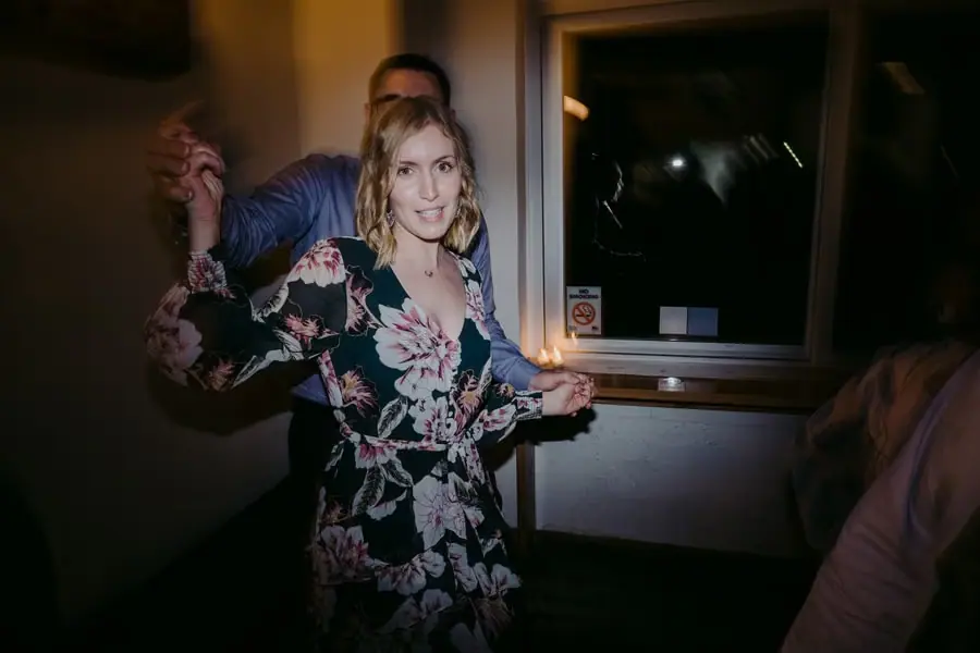 Guest in a floral dress smiling and raising her arms on the dance floor