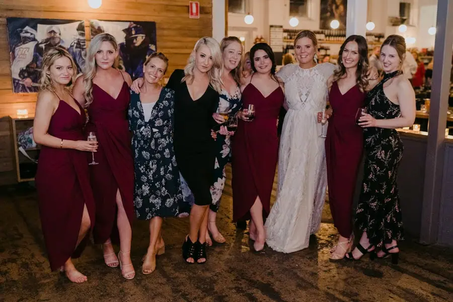 Bride posing with a group of women holding drinks at the reception