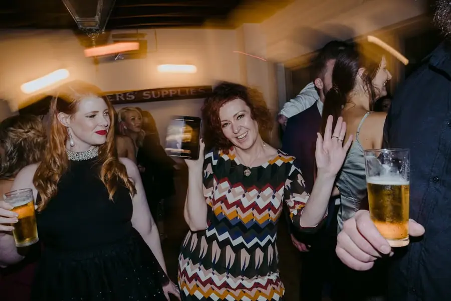 Two women laughing and dancing together with drinks