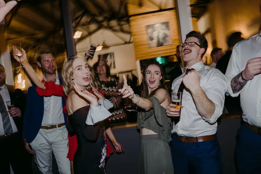 Guests singing and raising their arms on the dance floor