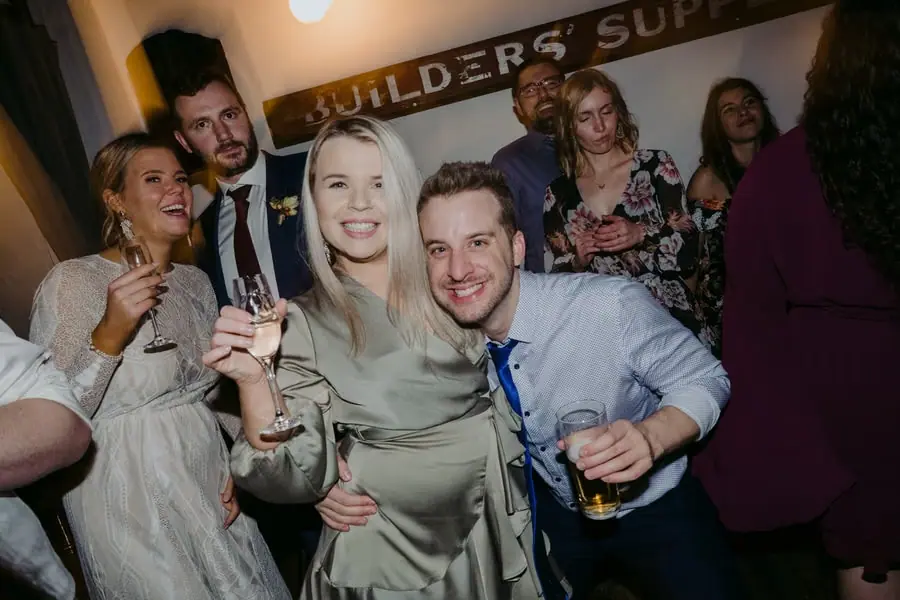 Smiling guests leaning together with drinks on the dance floor