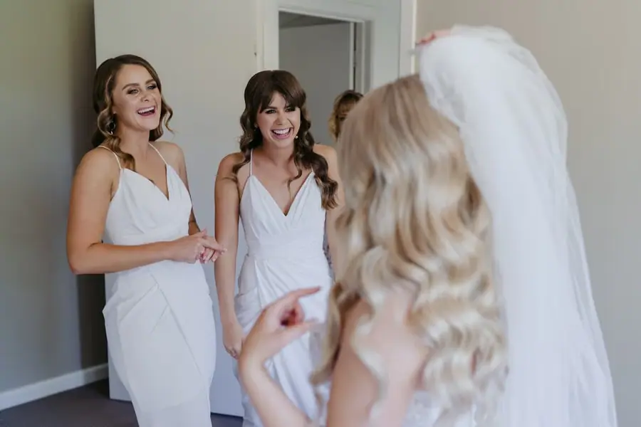 Bridesmaids smiling at the bride in her wedding dress