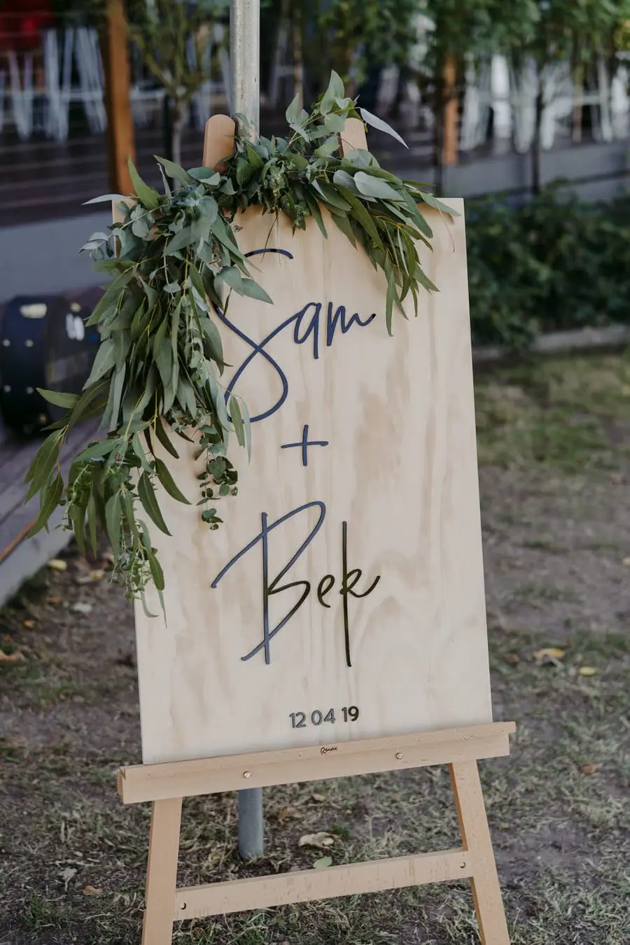 Wooden wedding welcome sign decorated with greenery