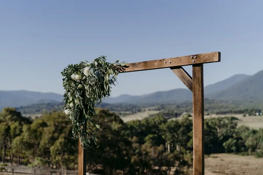 Wooden ceremony arch draped with greenery overlooking a valley