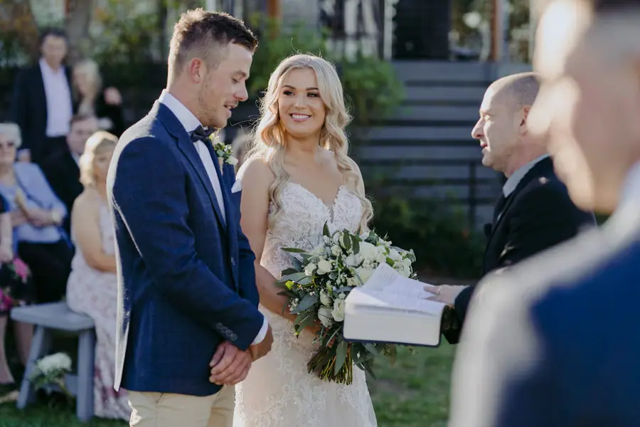 Bride smiling at the groom as the celebrant holds an open book