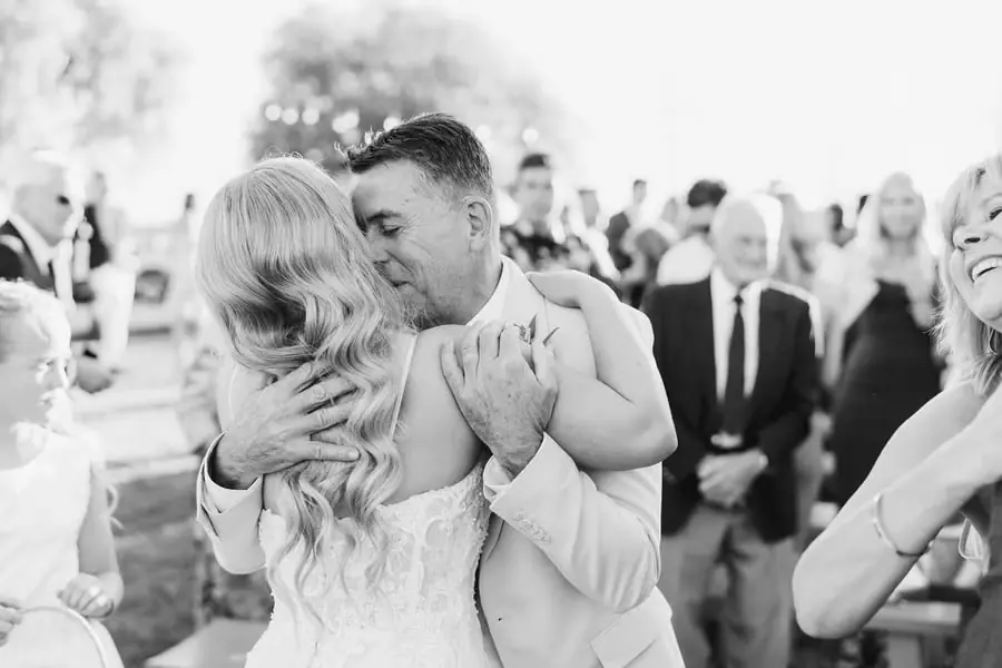 Black-and-white photograph of the bride embracing an older man