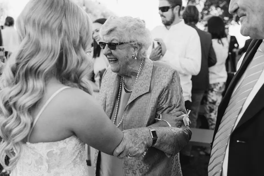 Black-and-white photograph of the bride greeting an older guest