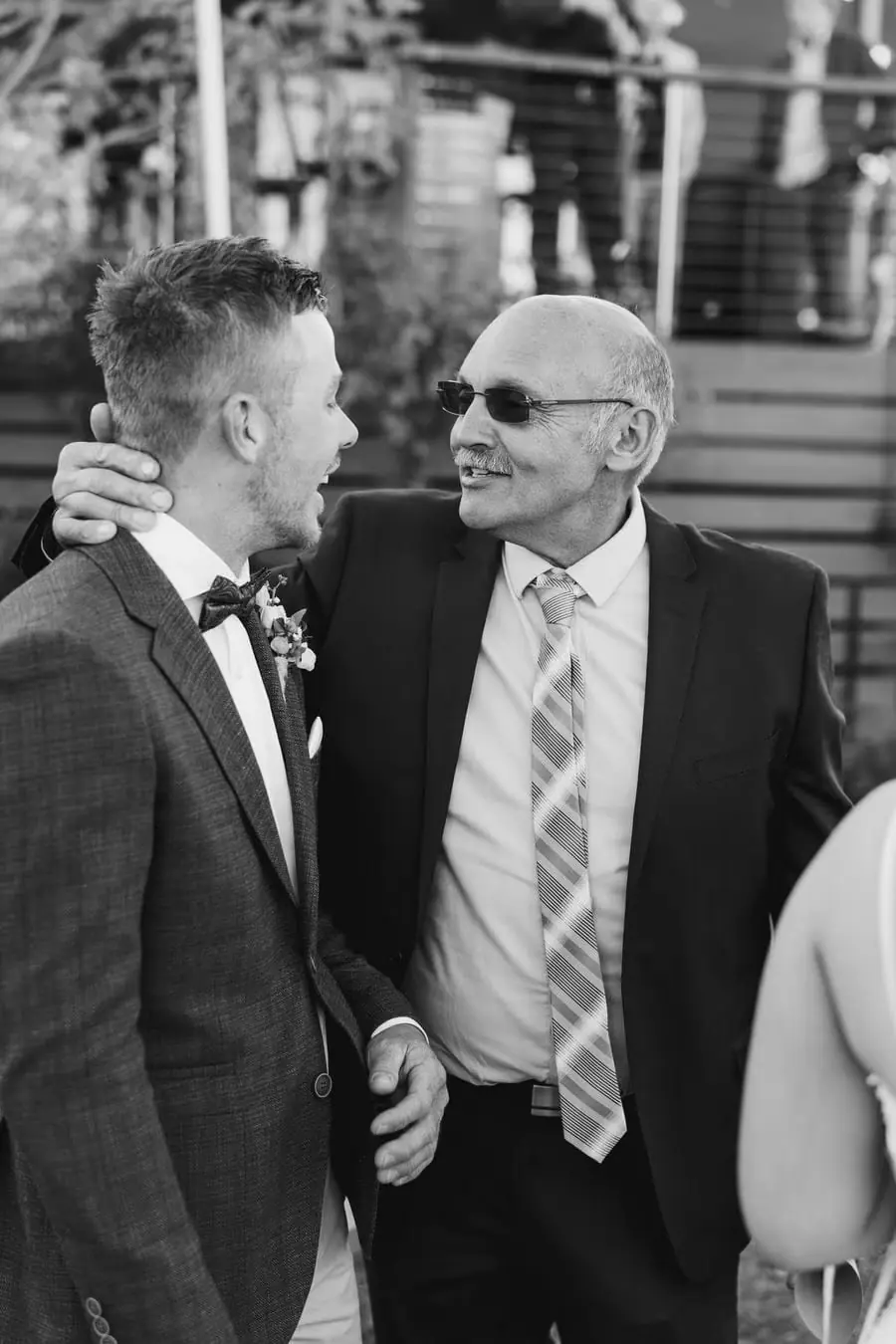 Black-and-white photograph of the groom with an older man in sunglasses