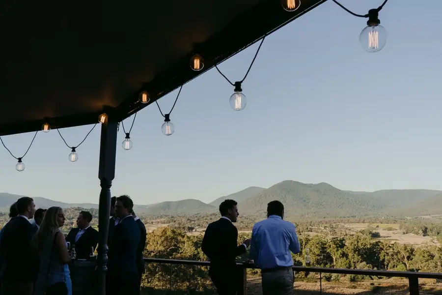 Guests looking across the valley beneath hanging light bulbs