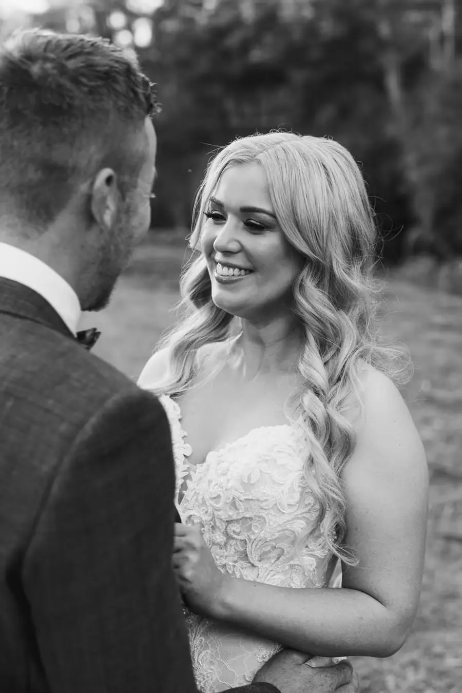 Black-and-white photograph of newlyweds smiling at each other