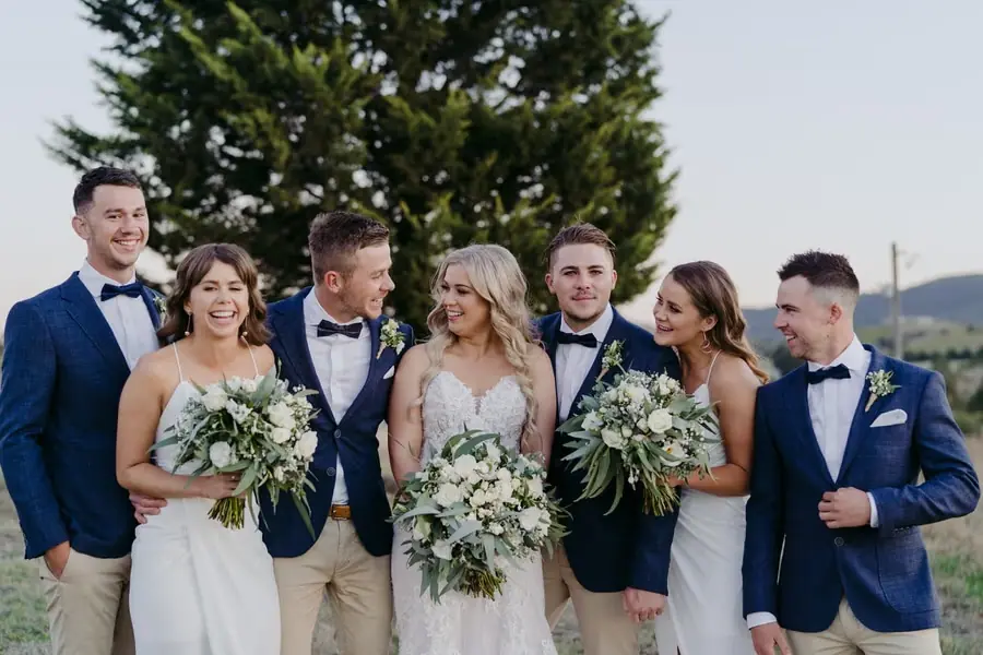 Wedding party laughing together beside a large tree
