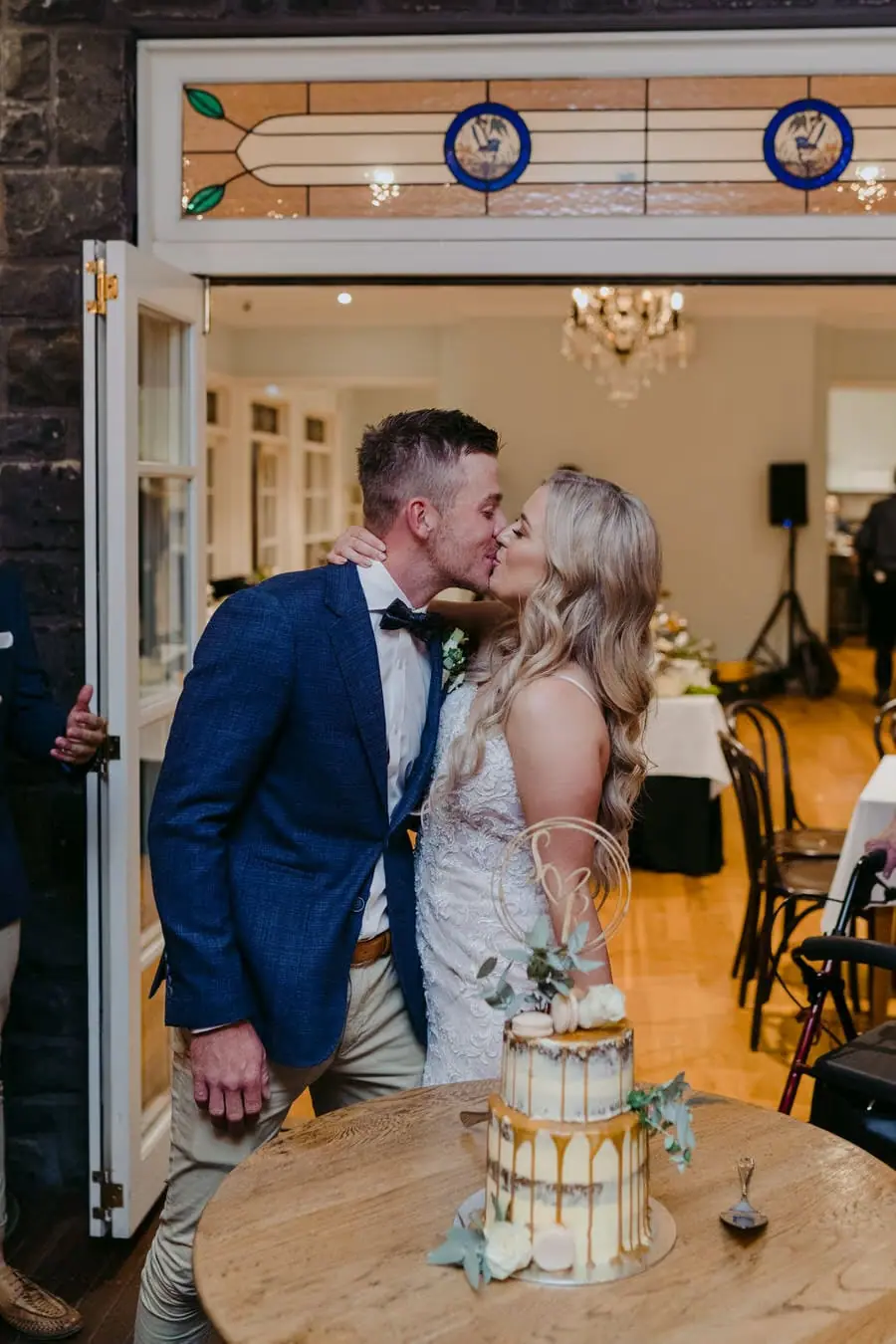 Newlyweds kissing beside their wedding cake