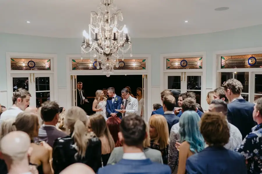 Guests gathered beneath a chandelier watching a speech