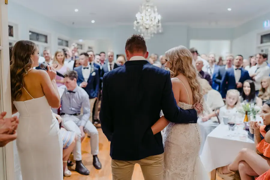 Bride and groom facing a roomful of seated guests