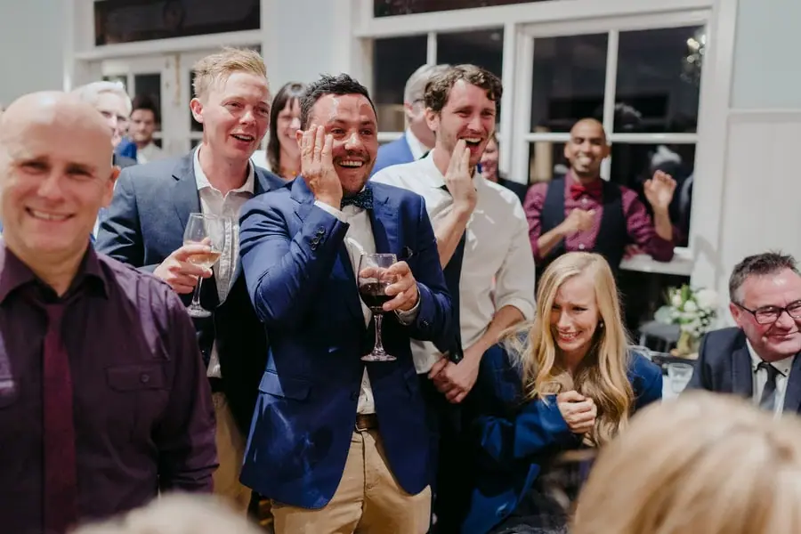 Guests laughing and holding drinks during the reception