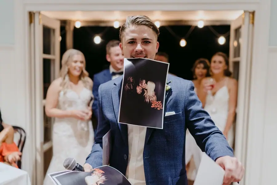 Groom smiling with a photograph held between his teeth