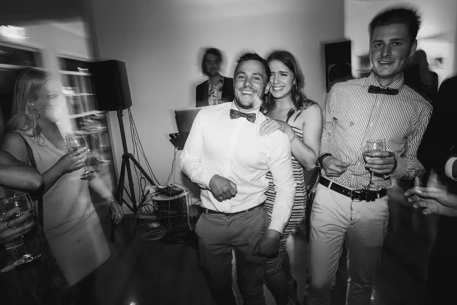 Black-and-white photograph of guests laughing together with drinks