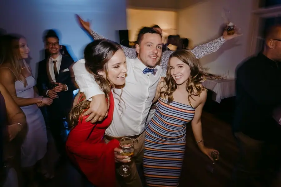 Guest dancing between two women on a crowded dance floor