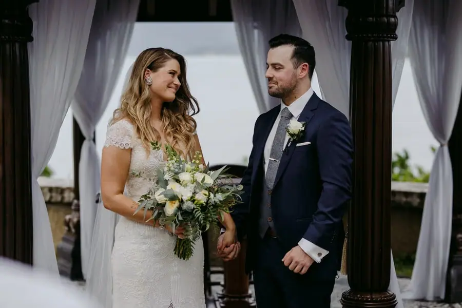Bride and groom smiling at one another beneath a curtained pavilion