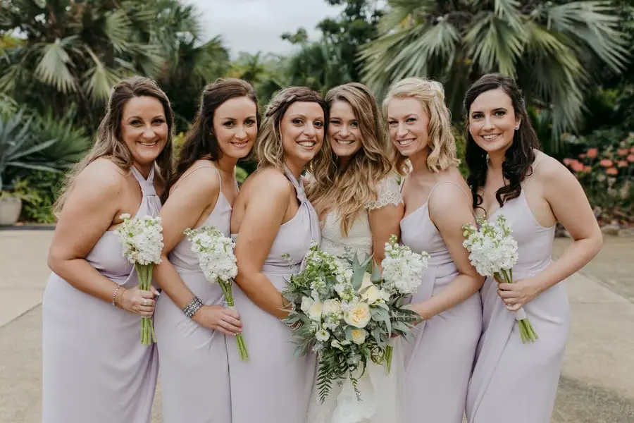 Bride and five bridesmaids smiling together with their bouquets