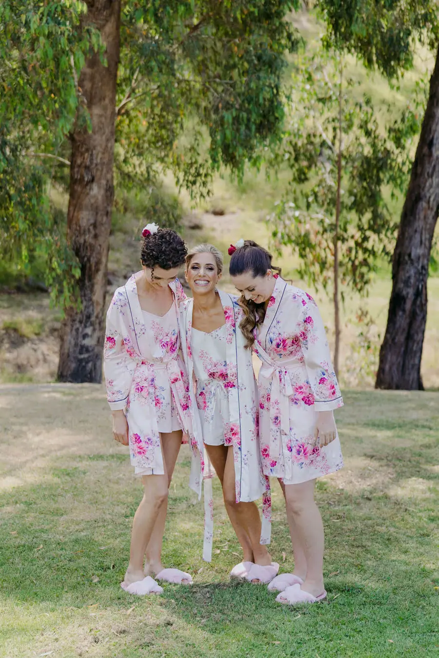 Three women in matching floral robes standing together on a lawn