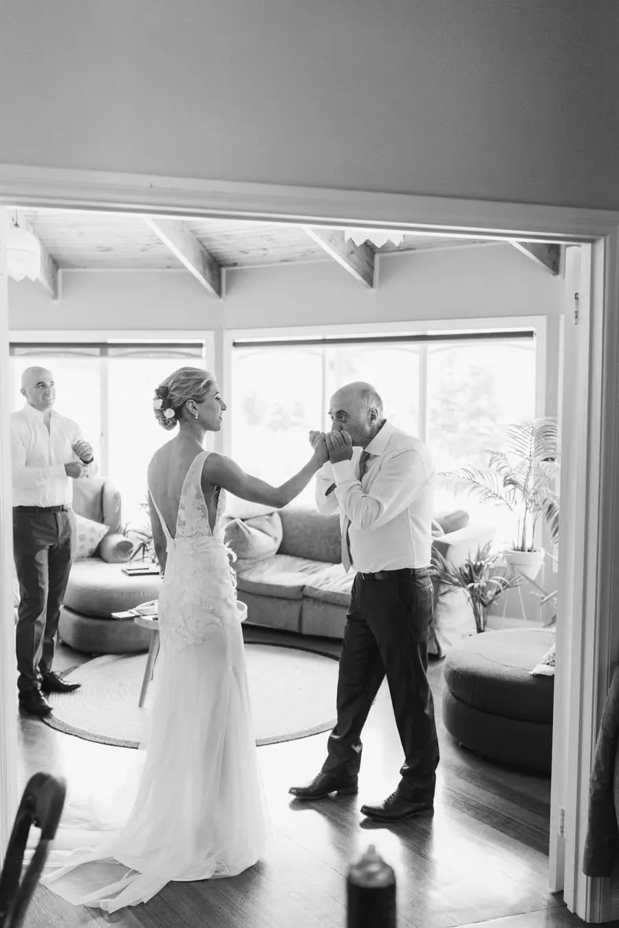 Black and white photograph of a man kissing the bride's hand indoors