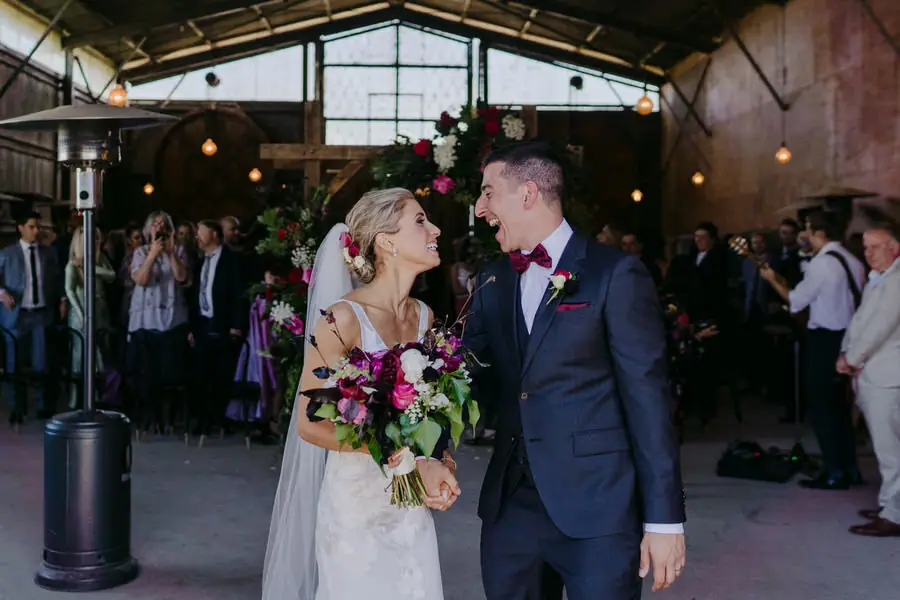 Bride and groom looking at each other beneath the floral ceremony arch