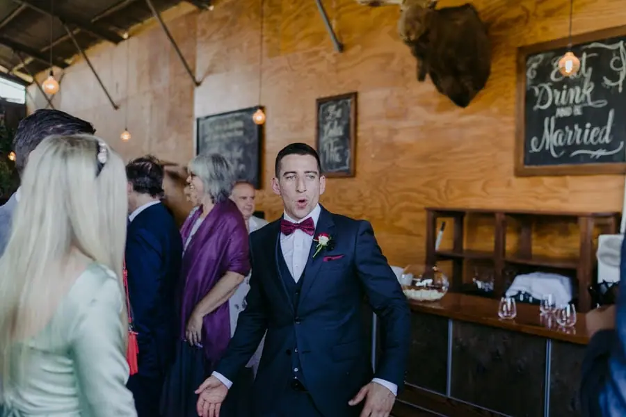 Groom chatting with wedding guests beside an indoor bar
