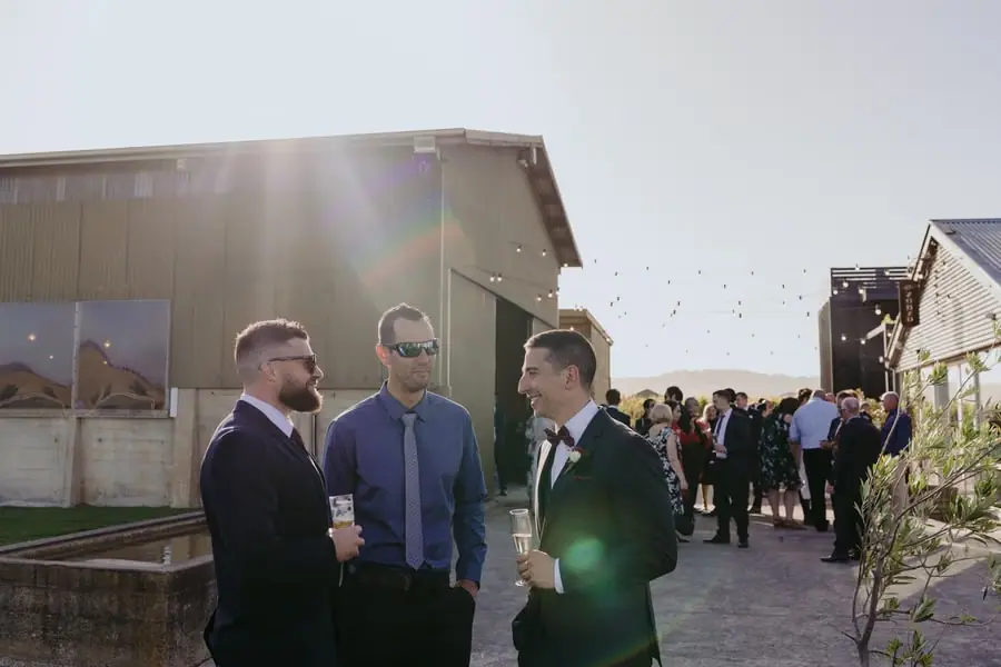 Three men sharing drinks outdoors in late afternoon sunlight