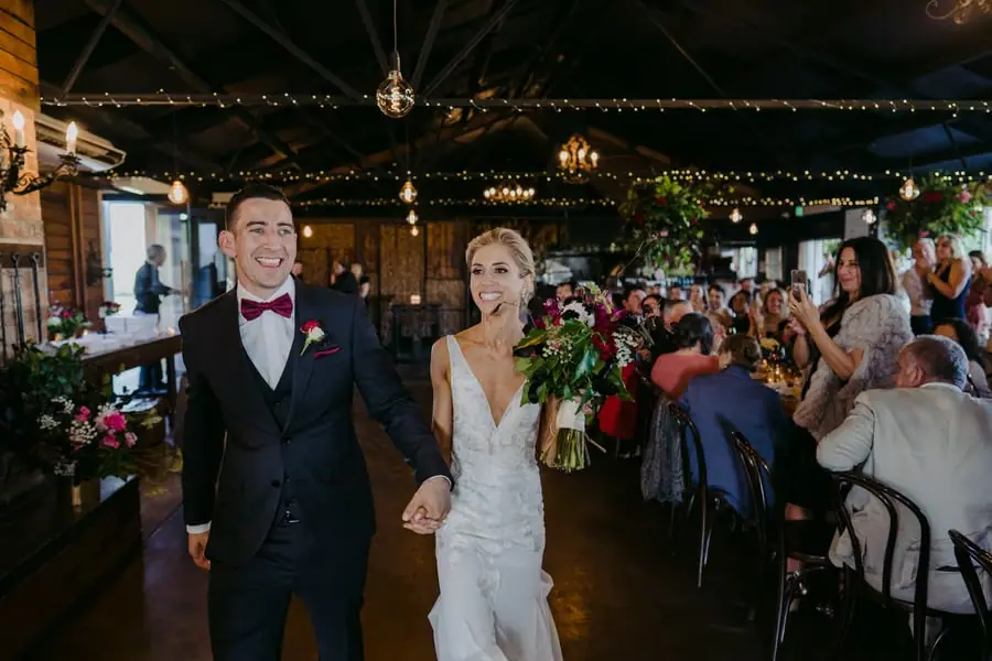 Bride and groom entering the reception as seated guests cheer