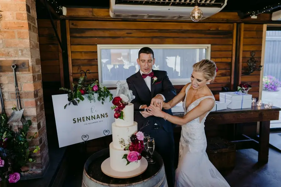 Bride and groom cutting their flower-decorated white wedding cake