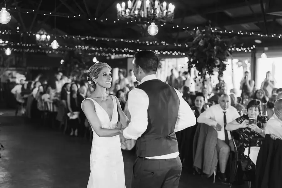 Black and white photograph of the bride and groom dancing as seated guests watch