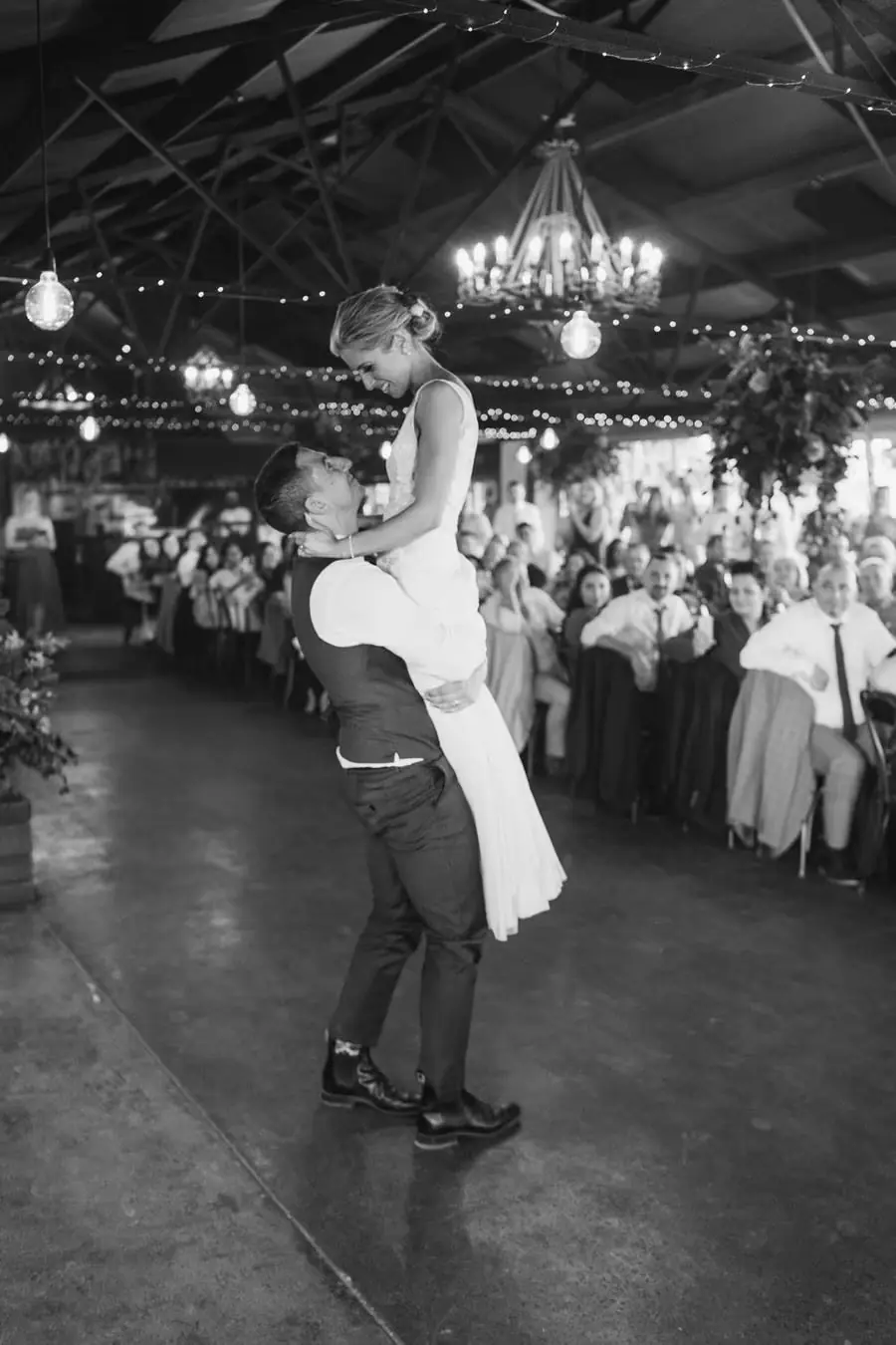 Black and white photograph of the groom lifting the bride on the dance floor