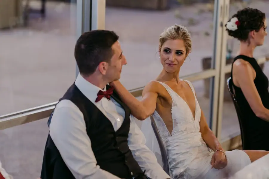 Bride resting her hand on the groom's shoulder while seated beside him