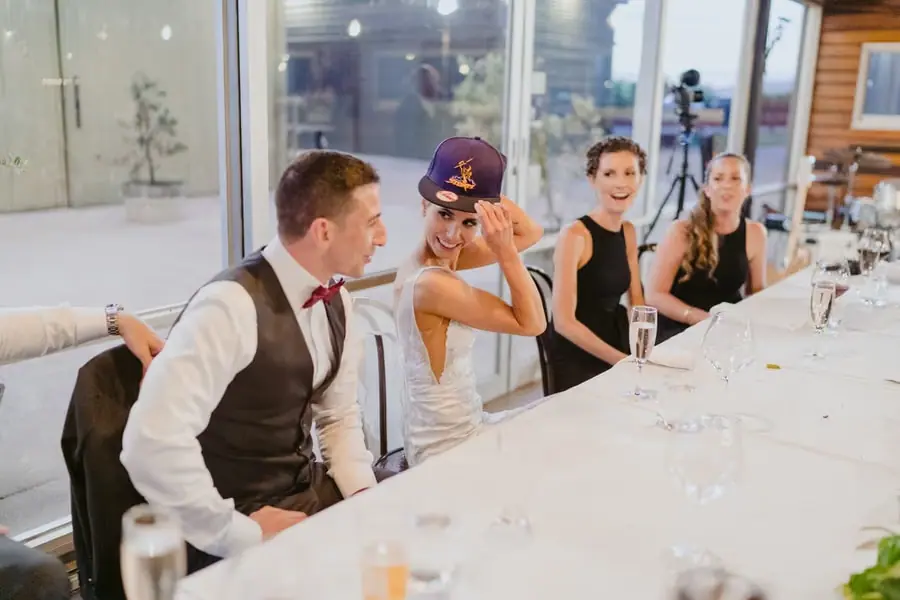 Bride wearing a purple cap while sitting with the groom and bridesmaids