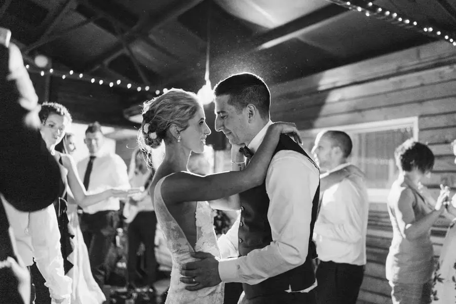 Black and white photograph of the bride and groom dancing beneath fairy lights