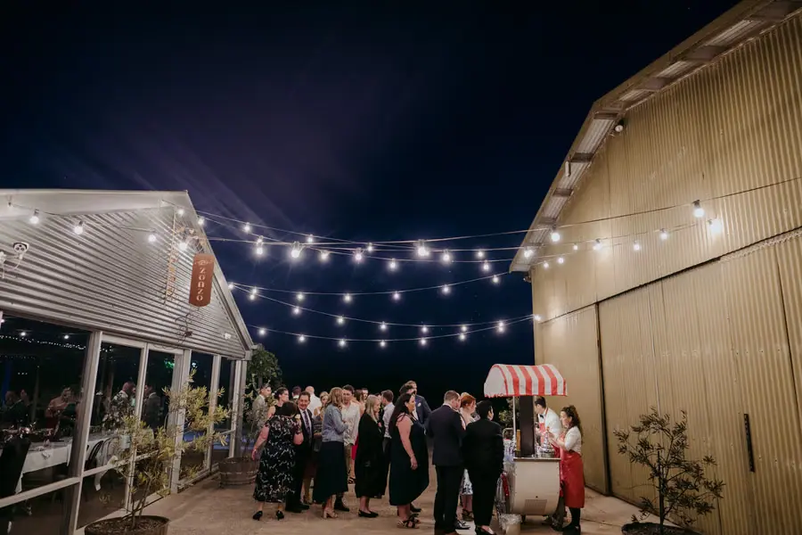 Wedding guests gathered in a courtyard beneath festoon lights after dark