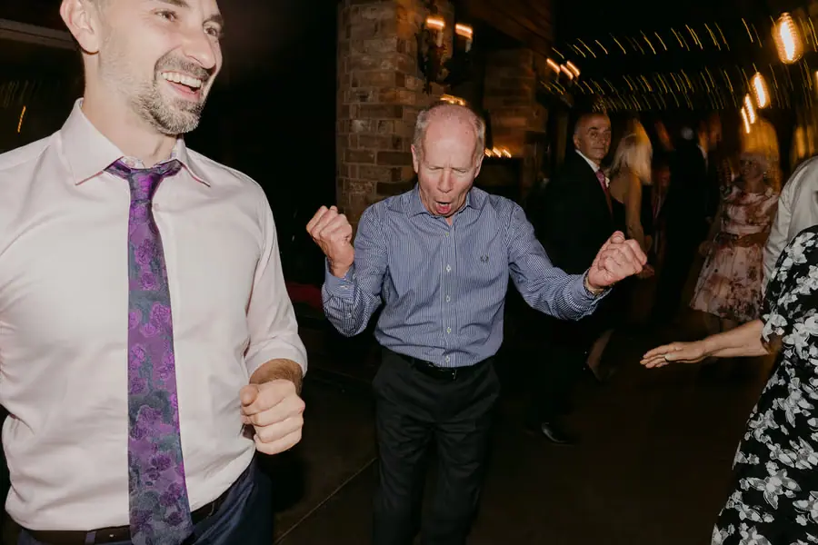 Guests dancing together beneath warm reception lights