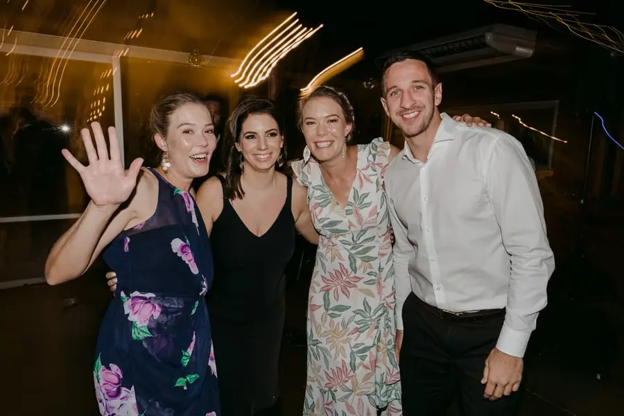 Four smiling guests posing together on the dance floor
