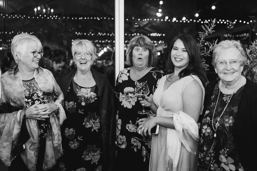 Black and white photograph of five women laughing together at the reception