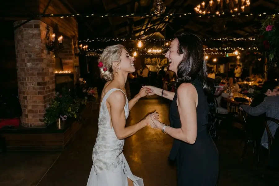 Bride and a bridesmaid laughing together on the dance floor